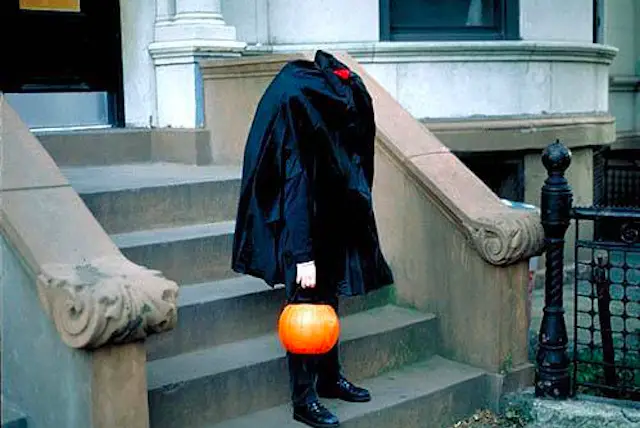 This is a photo of a headless man carrying a plastic pumpkin.